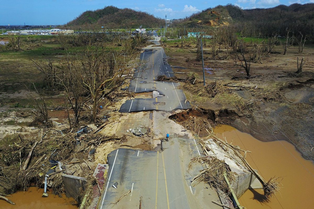 A man rides his bicycle through a damaged road in Toa Alta, west of San Juan, Puerto Rico, on September 24, 2017. RICARDO ARDUENGO/AFP/Getty Images